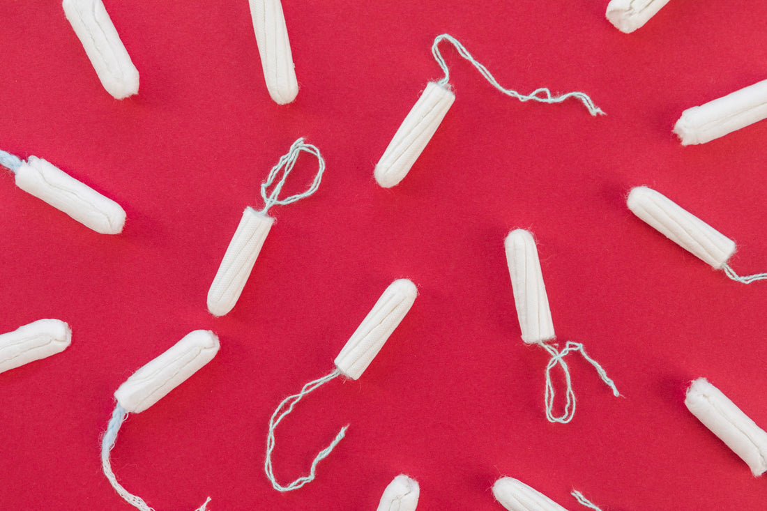Tampoane albe plasate pe fundal roșu intens, ilustrând produsele menstruale convenționale.