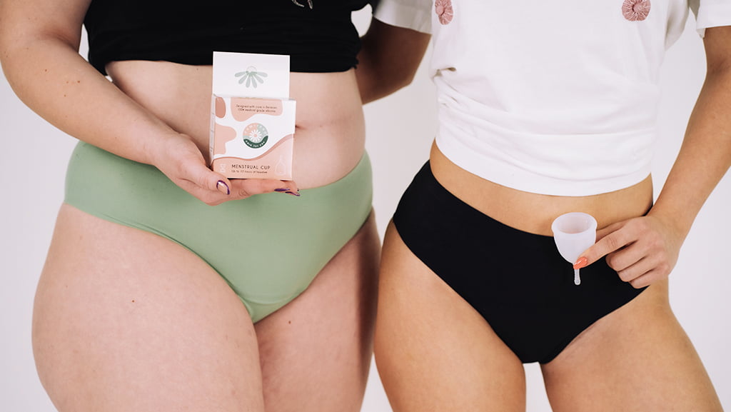 Două femei în lenjerie menstruală, una ținând o cutie cu cupa menstruală Femi.Eko®, cealaltă prezentând cupa – un simbol al diversității, confortului și alegerii sustenabile.