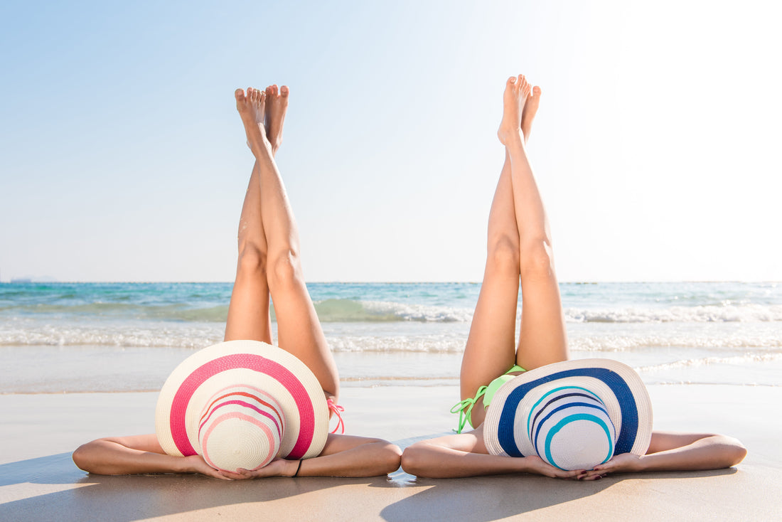 2 women on the beach with sun hats